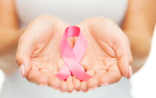 healthcare and medicine concept - womans hands holding pink breast cancer awareness ribbon